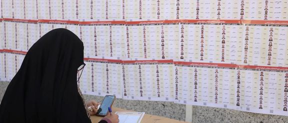 An Iranian woman checks the names of candidates during parliamentary elections at a polling station in Tehran, Iran, March 1, 2024.