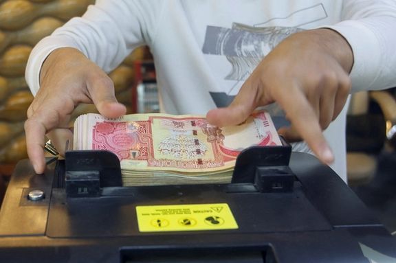 A man counts Iraqi dinars on a money counting machine at a currency exchange shop in Baghdad, Iraq, January 23, 2023.