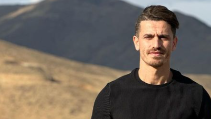 a man in a black sweater stands in front of a mountain