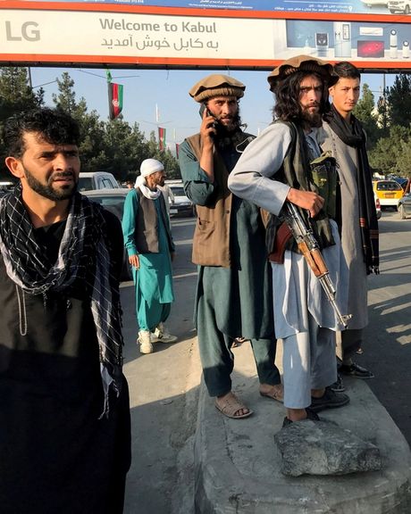 A member of Taliban (center) stands outside Hamid Karzai International Airport in Kabul, Afghanistan, August 16, 2021.