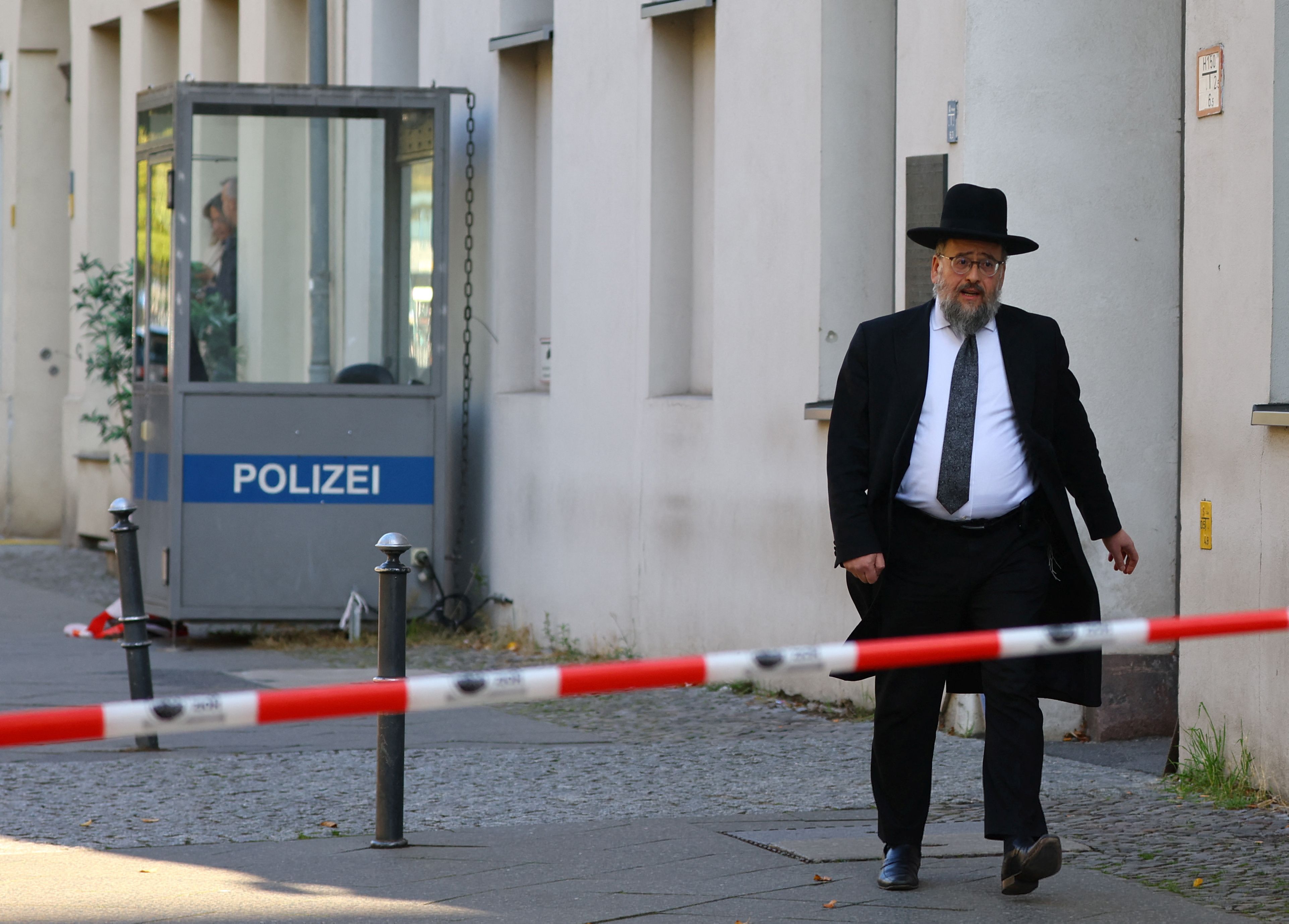 A member of the Jewish community walks behind barrier tape following a police lockdown of the area after two Molotov cocktails were thrown at the Skoblo Synagogue and Education Center overnight in Berlin, Germany, October 18, 2023. 