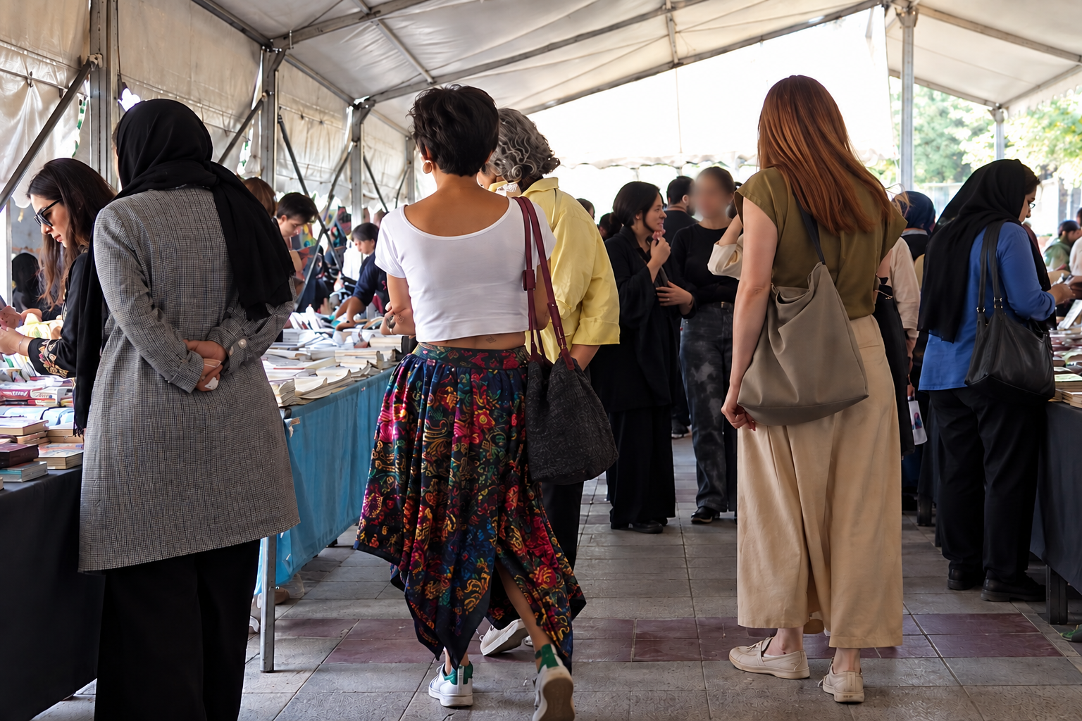 Iranian women without the mandatory hijab browse stalls at an outdoor market in August 2026.