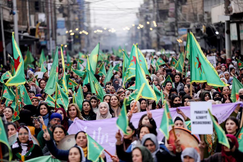 زنان با پرچم‌های یگان‌های مدافع زنان در تجمعی در قامشلی سوریه، سوم دی ۱۴۰۳