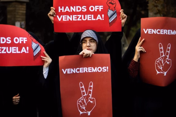 Protesters hold up posters in support of Venezuela, in front of the Swiss embassy in Tehran, which represents US interests in Iran, November 2025