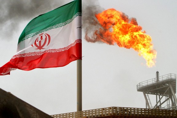 A gas flare on an oil production platform is seen alongside an Iranian flag in the Persian Gulf