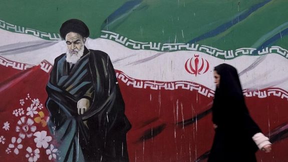 A woman walks past a painting of Iran's late leader Ruhollah Khomeini in Tehran, File Photo.