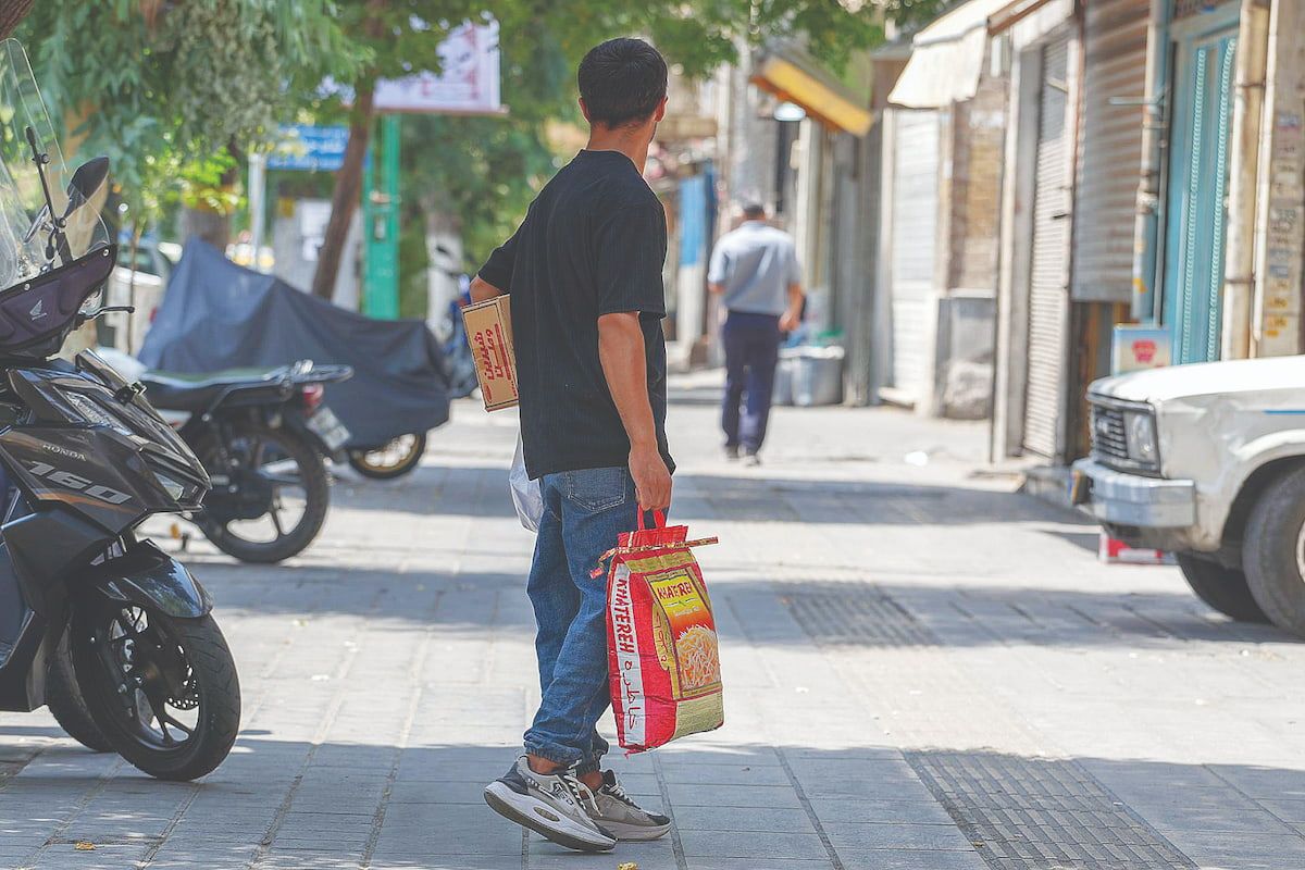 A shopper carries groceries in Iran. Rising prices and declining purchasing power have pushed basic food items to the center of the country's widening cost-of-living crisis.