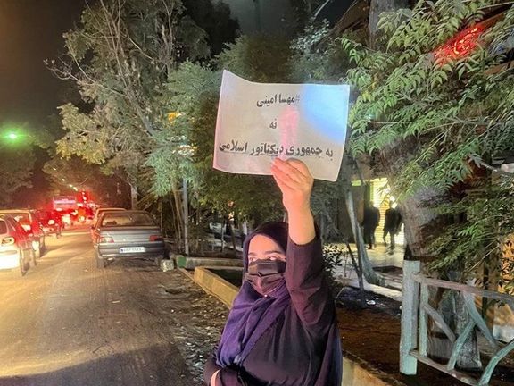 A lone woman in the street holding a sign that says, "NO to the dictatorial Islamic Republic