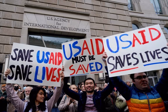People hold placards, as the USAID building sits closed to employees after a memo was issued advising agency personnel to work remotely, in Washington, DC, February 3, 2025.