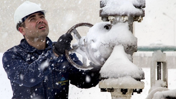 An Iranian energy worker adjusts a valve amid heavy snowfall, highlighting the challenges of maintaining gas flow during winter months. (Undated)
