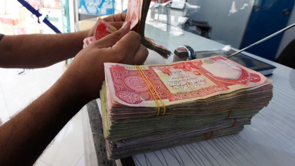 A customer counts Iraqi dinars at a money changer in Baghdad.