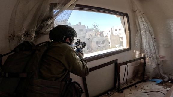 An Israeli soldier fires a weapon from a window during operations in the Gaza Strip. (December 2023)