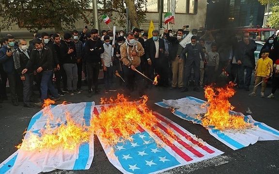 Iranian regime supporters burning American and Israeli flags in November 2021