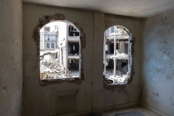 A destroyed building can be seen through the shattered windows of a room opposite, Tehran, Iran, July 4, 2025