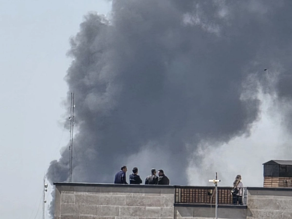 Residents watch as a large plume of smoke rises over Tehran following Israeli-US strikes (undated).