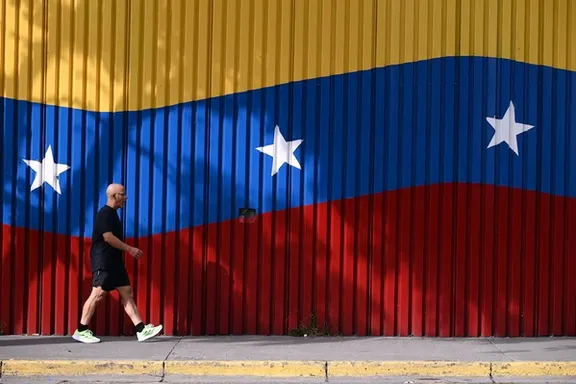 A man walks past a mural with the colors of the Venezuelan flag, after US President Donald Trump said that the airspace above and around Venezuela would be completely closed, amid rising tensions between the Trump administration and the government of Venezuelan President Nicolas Maduro, in Caracas, Venezuela, November 29, 2025.