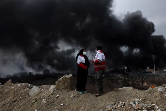 Members of the Red Crescent talk to each other as smoke rises after a reported strike on Shahran fuel tanks, amid the US-Israeli conflict with Iran, in Tehran, Iran, March 8, 2026.