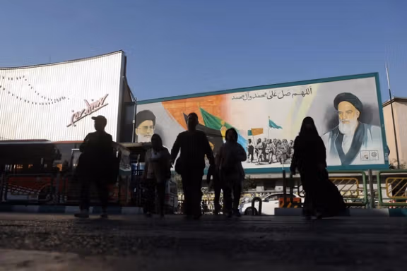People walk next to a mural with a picture of Iran's Supreme Leader, Ali Khamenei, on a street in Tehran, Iran, November 5, 2025.