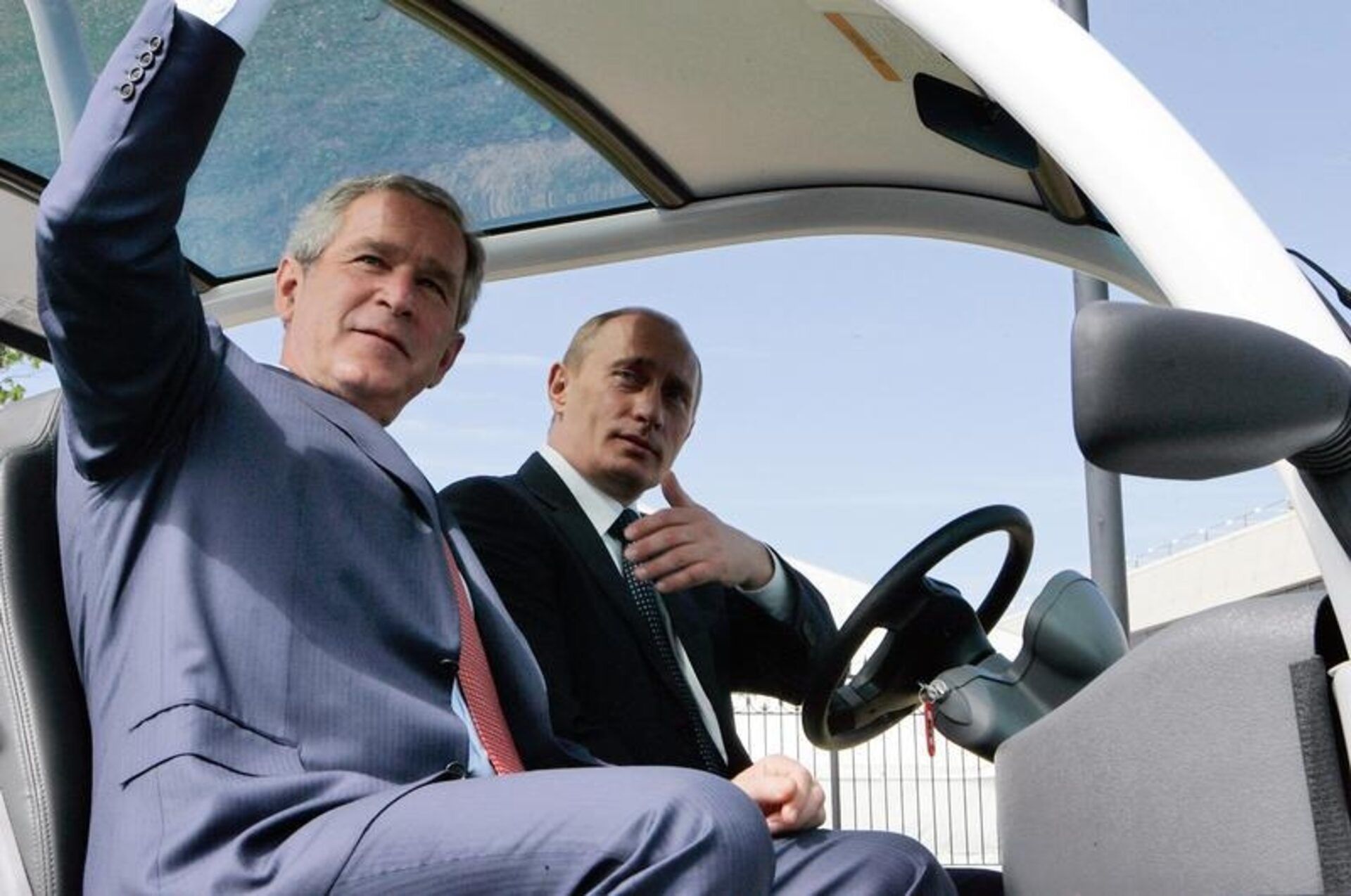 Former US president George W. Bush (left) and Russian President Vladimir Putin sit in an electric micro-car before the official start of the G8 summit outside of St Petersburg July 15, 2006. 