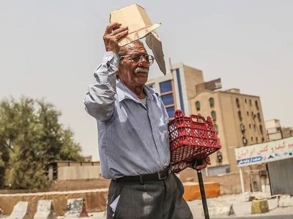 An elderly man shields himself from the scorching sun with a piece of cardboard amid a heatwave in Iran