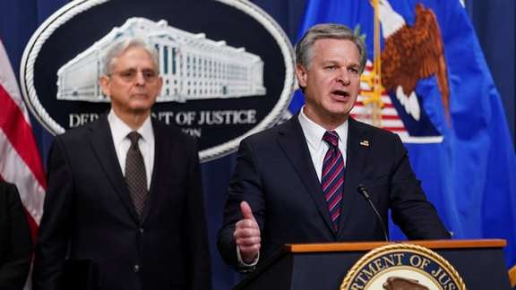 FBI Director Christopher Wray is flanked by U.S. Attorney General Merrick Garland, as he discusses charges against three members of an Eastern European criminal organization with ties to Iran's government with conspiring to assassinate a journalist and activist who is a U.S. citizen, during a news conference at the Justice Department in Washington, U.S., January 27, 2023