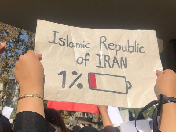 A university student in Tehran in November holding up a sign showing government power in decline