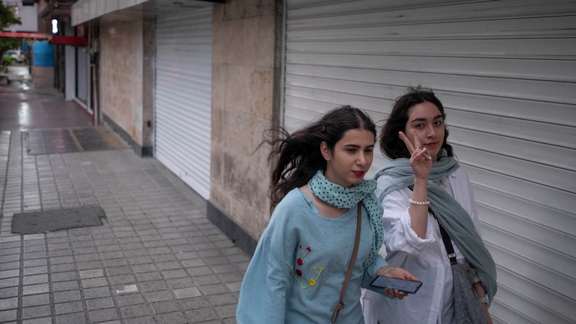 Two Iranian women walk along a street-side in the strong winds without wearing the mandatory Islamic headscarf in downtown Tehran,on June 8, 2023.