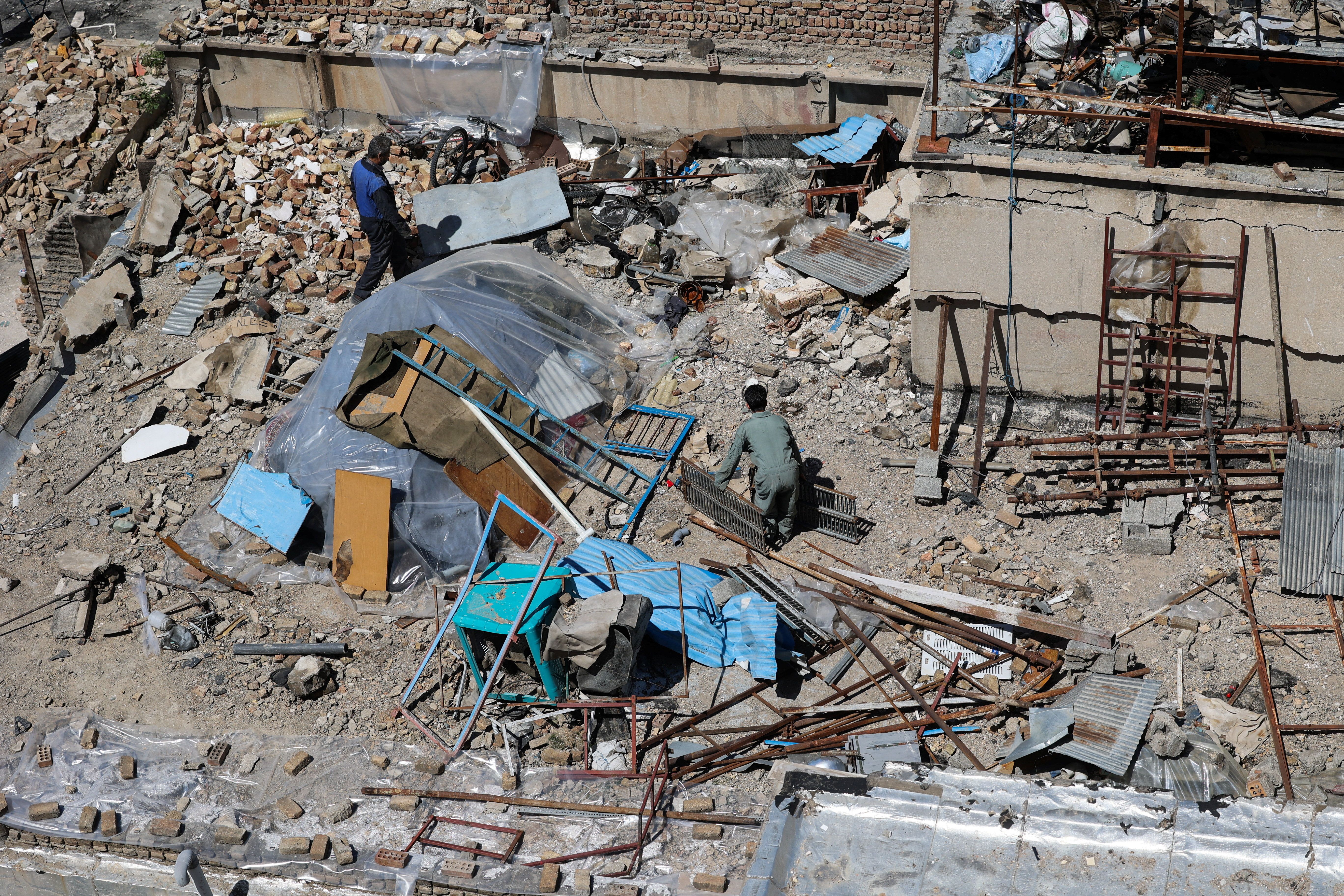 People inspect the site of a residential building damaged by a strike, amid the US-Israeli conflict with Iran, in Karaj, Iran, April 3, 2026. 