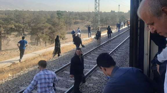 Commuters walk along the tracks after a breakdown halted trains on Tehran’s Line 5 metro linking the capital and Karaj on October 21, 2025.