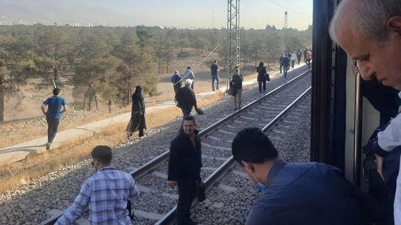 Commuters walk along the tracks after a breakdown halted trains on Tehran’s Line 5 metro linking the capital and Karaj on October 21, 2025.