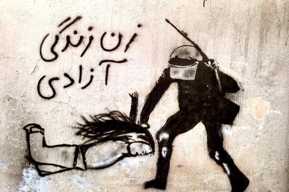 A graffiti image purportedly shows an Iranian security officer striking an unveiled woman, with the caption “Woman, Life, Freedom.”
