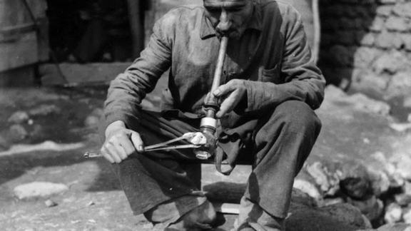 An Iranian man smokes opium using a traditional pipe