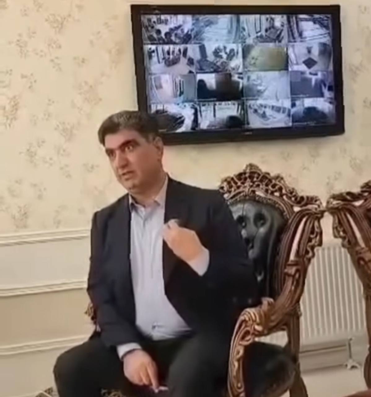 تصویری از خسرو علی‌کردی در مقابل تصاویر دوربین‌های دفتر کارش