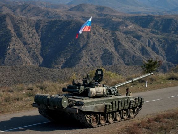 A service member of the Russian peacekeeping troops stands next to a tank near the border with Armenia, following the signing of a deal to end the military conflict between Azerbaijan and ethnic Armenian forces, in the region of Nagorno-Karabakh, November 10, 2020.