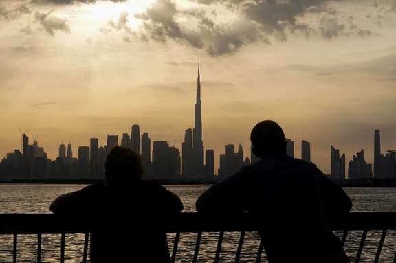 People way the sunset over Dubai, with a general view of the Dubai skyline, including Burj Khalifa, center, amid the US-Israel conflict with Iran, in United Arab Emirates, March 6, 2026.