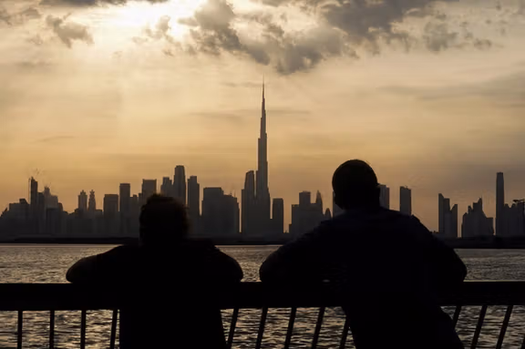 People way the sunset over Dubai, with a general view of the Dubai skyline, including Burj Khalifa, center, amid the US-Israel conflict with Iran, in United Arab Emirates, March 6, 2026.