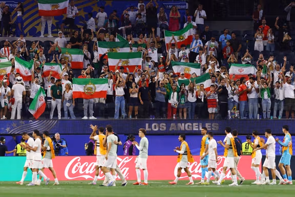 Iran players walk past Iranian fans holding official and pre-revolutionary flags, in Los Angeles, US, June 16, 2026