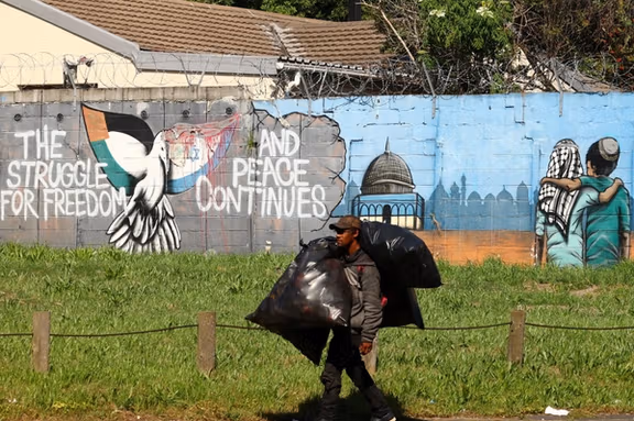 A man carries bags as he walks past a mural symbolising freedom and peace between Israel and Palestinians, in Rondebosch, Cape Town, South Africa, October 11, 2023.