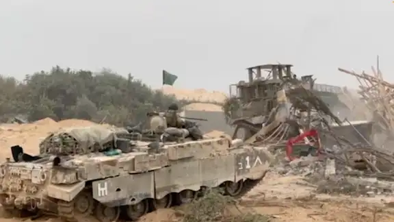 An Israel Defense Forces (IDF) armored vehicle waits as an armored bulldozer clears a debris-strewn path in a location given as Gaza. Octo. 29, 2023