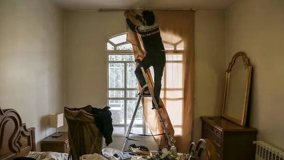An Iranian man installs curtains at home as part of preparations ahead of the Nowruz new year celebrations.