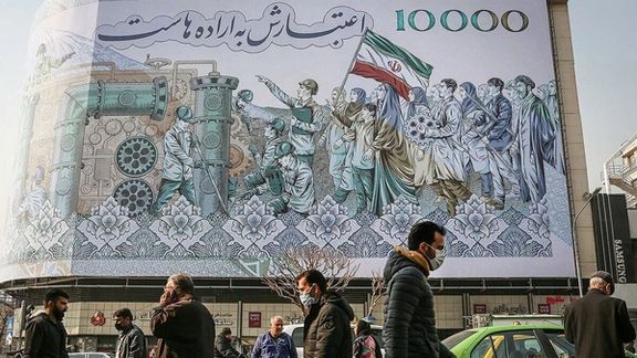 People walking past a mural at Tehran’s Enqelab square showing the Iranian 10,000-rial banknote worth less than two cents now