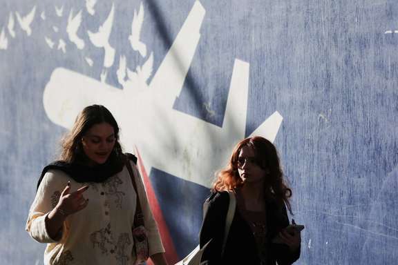 Iranian women walk past an anti-US mural on a street in Tehran, Iran, October 14, 2025.