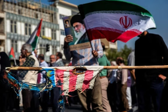 Protesters wave Iran's flag and burn that of the United States, in a rally to support the people of Gaza, Tehran, October 10, 2025