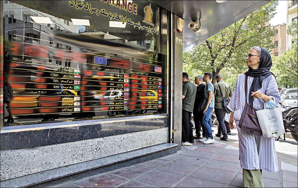 A woman walks past a currency exchange displaying foreign exchange rates in Tehran, Iran.