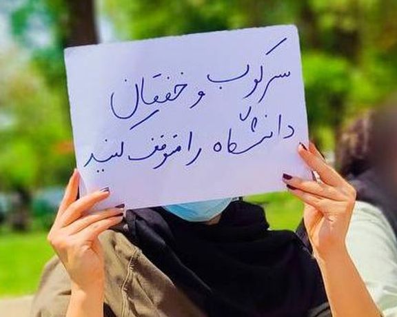 A student holding a sign condemning repression at Iranian universities