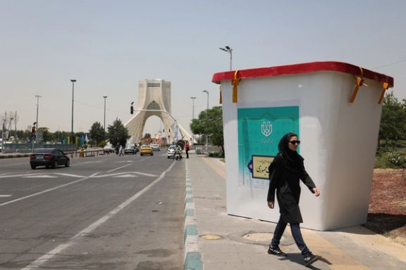 An Iranian woman walking past a huge mock ballot box in Tehran (June 2024)