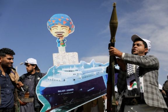 A Houthi follower holds a rocket launcher as others carry a cutout banner, portraying the Galaxy Leader cargo ship which was seized by Houthis in Sanaa, Yemen, February 7, 2024.