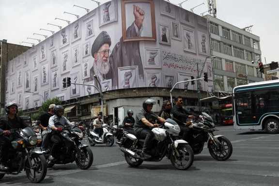 Motorcycles ride past a billboard depicting Iran's slain Supreme Leader Ali Khamenei, on a street in Tehran, June 2026