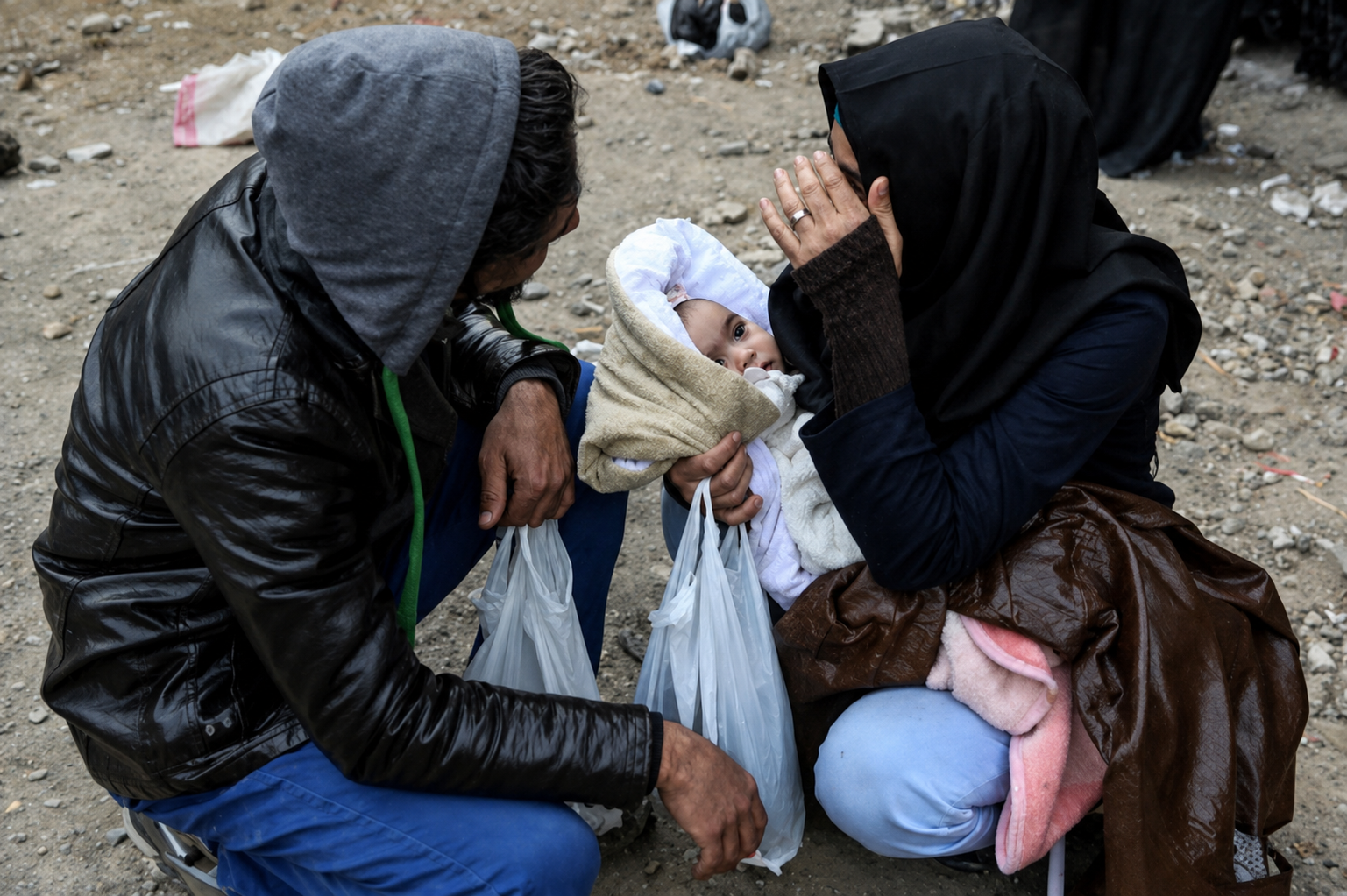 A woman with drug addiction holds a baby as a man sits beside her on a roadside in Iran in an undated image.
