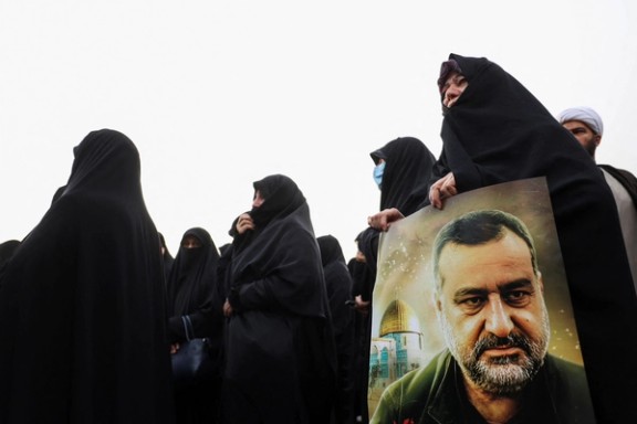 An Iranian woman carrying a poster of senior Iranian Revolutionary Guard general Razi Mousavi during his funeral service in Tehran (December 2023)